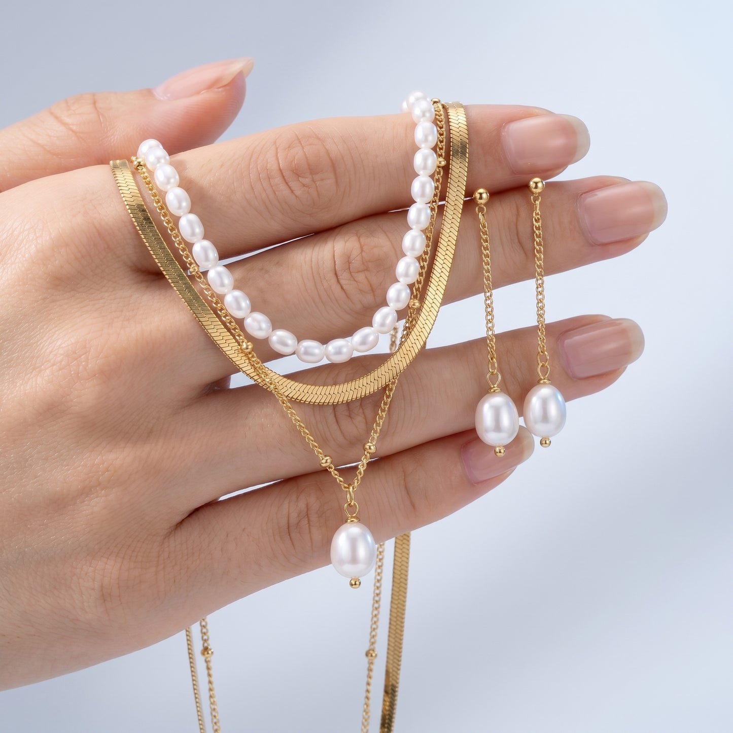 Set Dolce Vita Perla — Collana + Orecchini Oro 18K - scala reale tra le dita di una mano - UpperEast Jewels