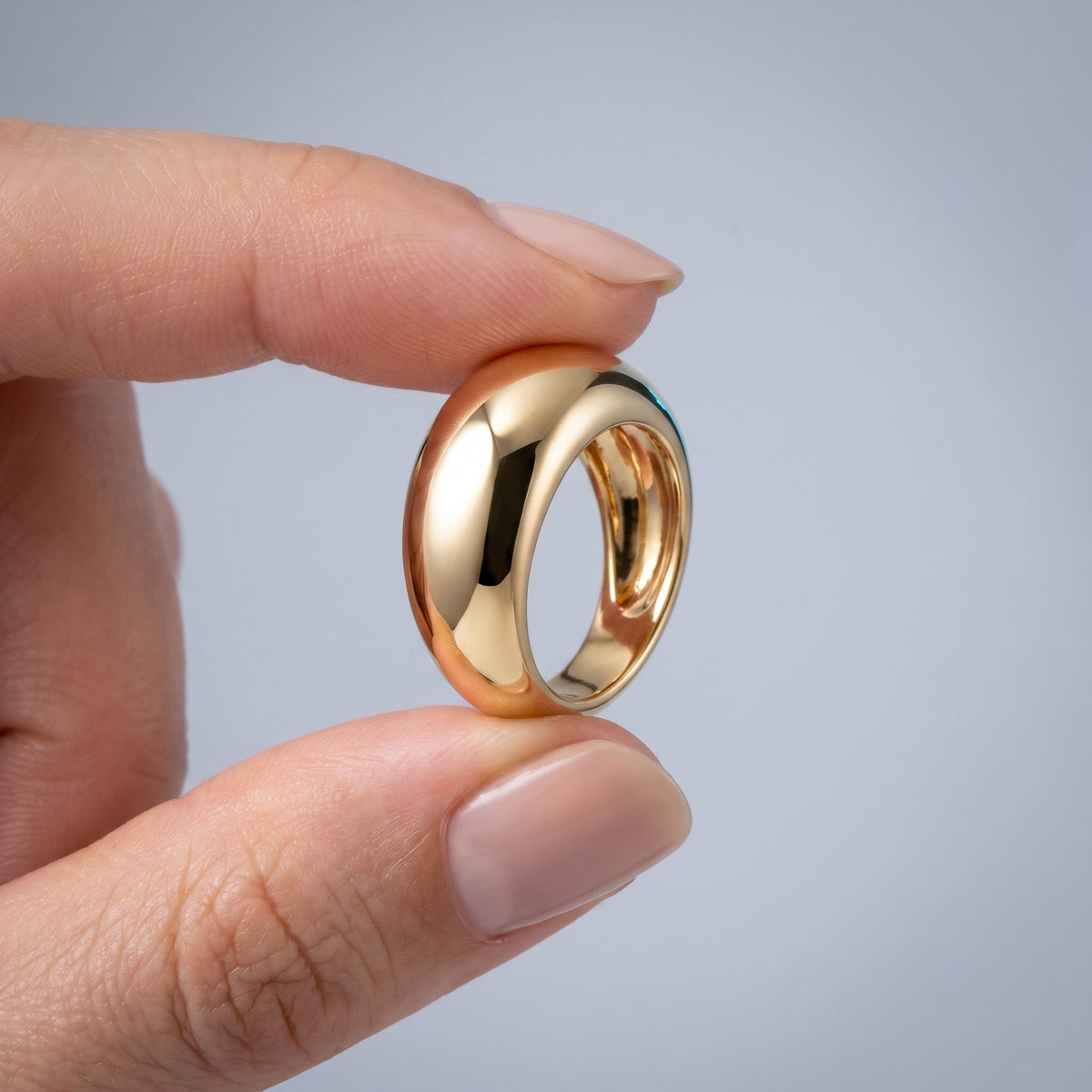 18K gold plated plain dome ring held between the fingers to show the real size