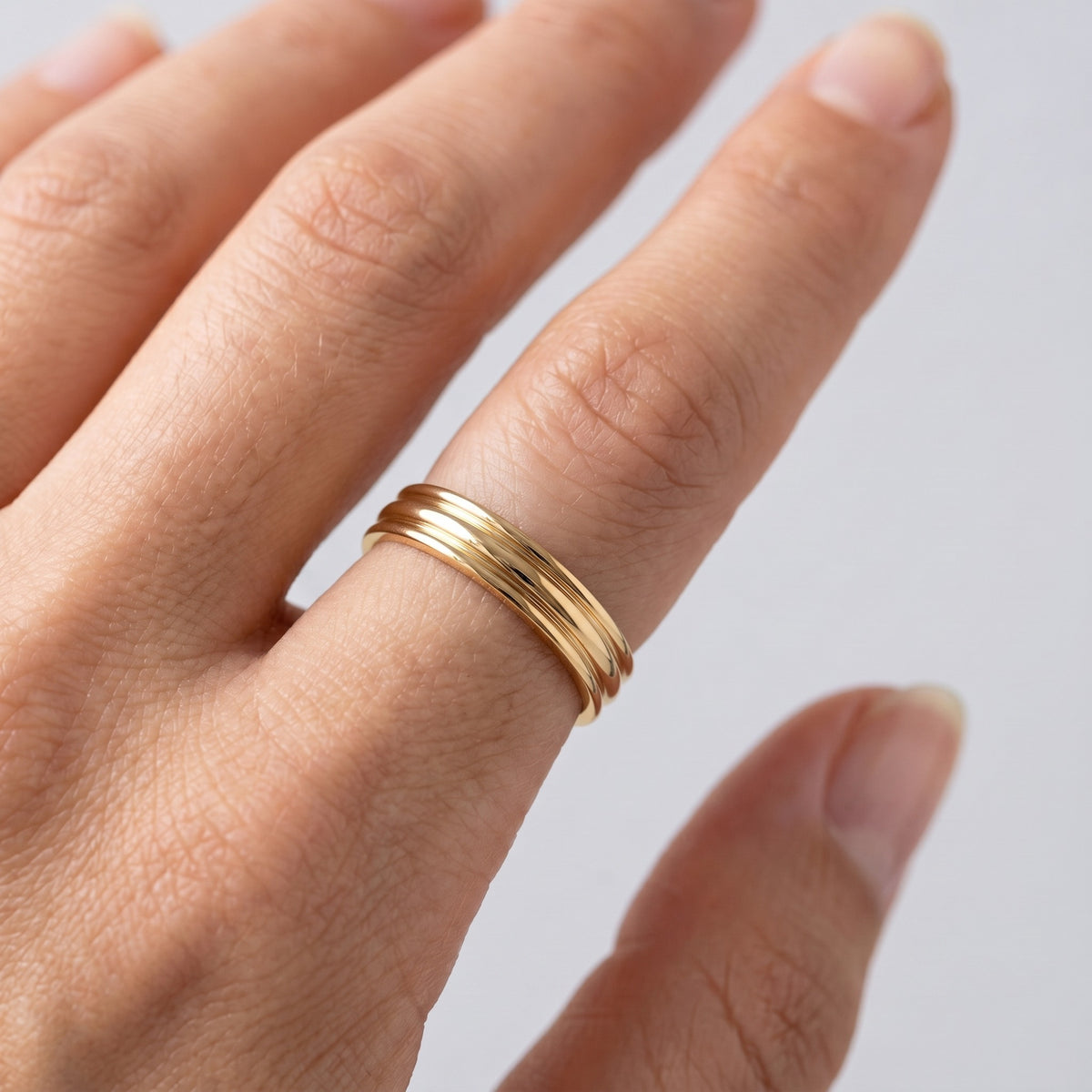 Anillo triple de ceremonia bañado en oro de 18K puesto, primer plano