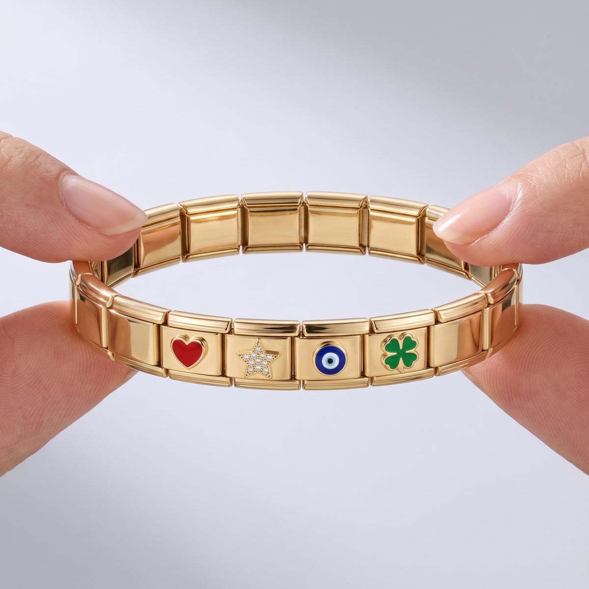 Bracciale componibile con charm placcato oro 18K tenuto tra le dita, per vedere le dimensioni reali