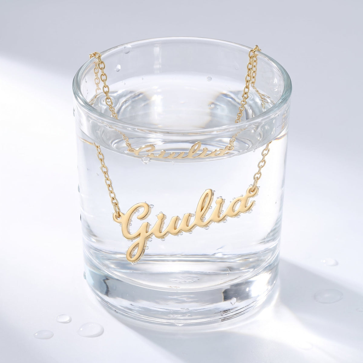 Collana nome in corsivo placcata oro 18K in un bicchiere d'acqua